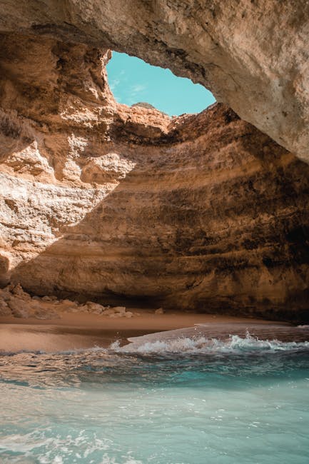 Captivating view of a beach cave in Algarve with turquoise waters and rock formations.